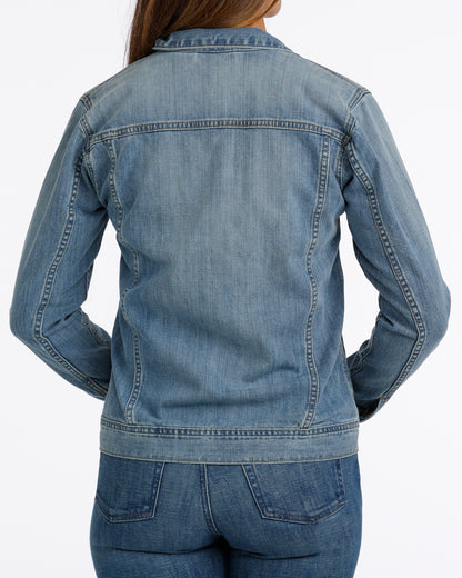 woman wearing a Cinch jean jacket, and blue jeans on a grey background