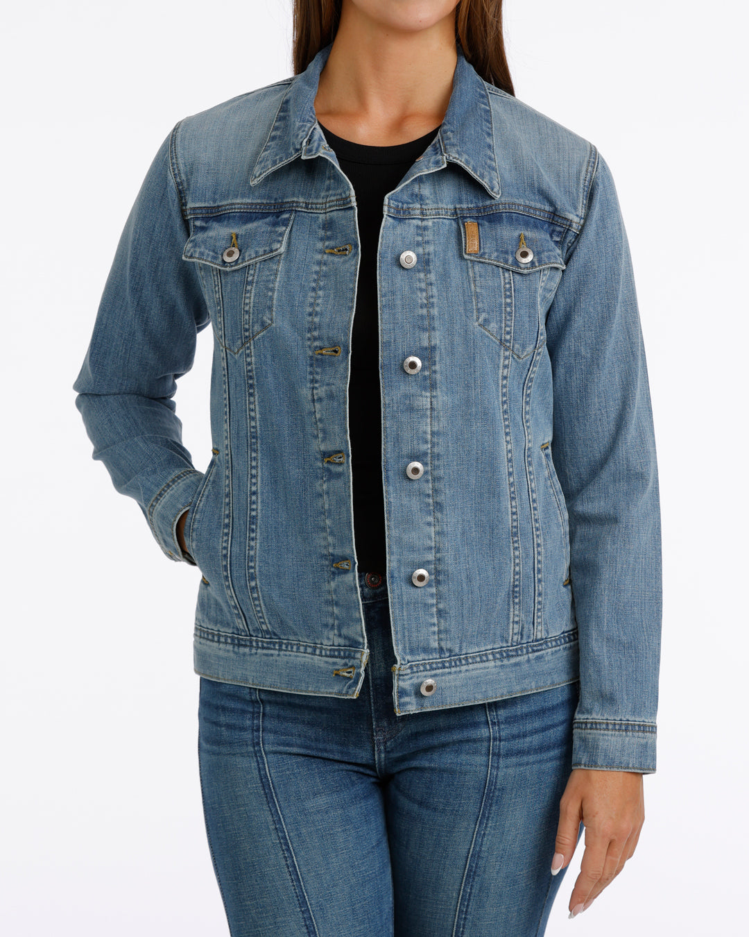 woman wearing a Cinch jean jacket, and blue jeans on a grey background