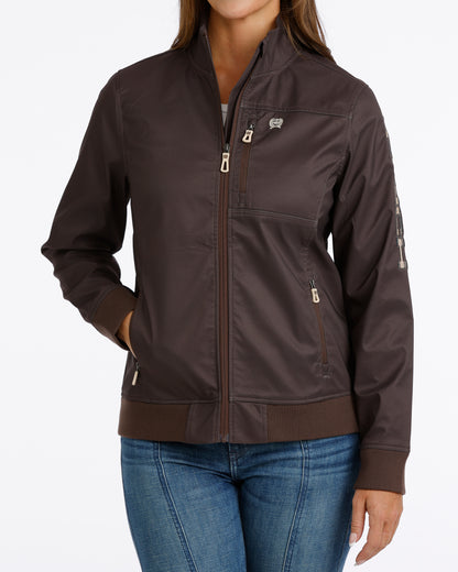 Woman wearing a brown Cinch jacket and blue jeans on a white background