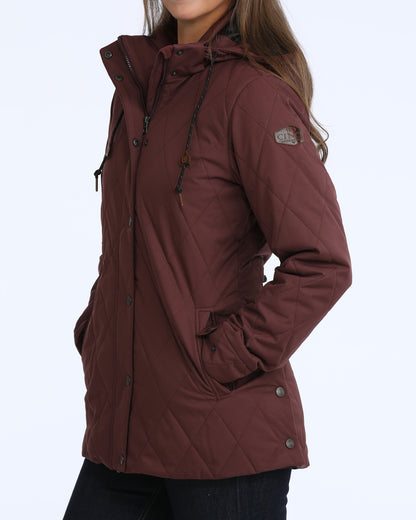 woman wearing a purple Cinch jacket and dark blue jeans on a grey background