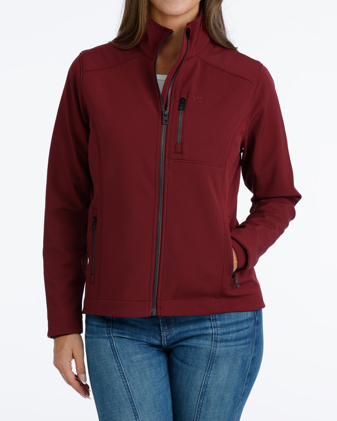 woman wearing a burgundy Cinch jacket and blue jeans on a white background