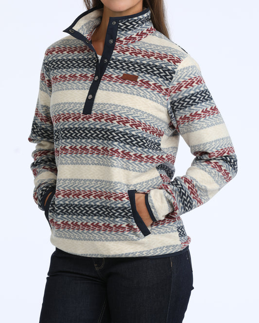 woman wearing a multi colored fleece Cinch sweater and blue jeans on a white background