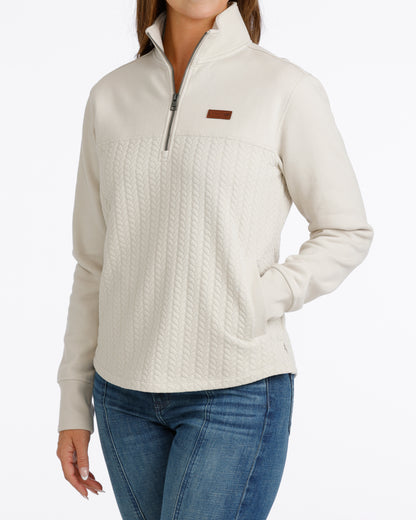 woman wearing a cream Cinch pullover sweater and blue jeans on a white background