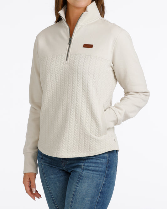 woman wearing a cream Cinch pullover sweater and blue jeans on a white background