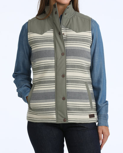 Woman wearing a green and blue Cinch vest, denim shirt and dark blue jeans on a white background