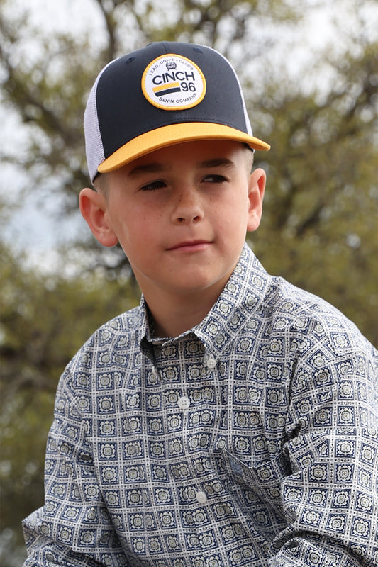 Young boy wearing a Cinch cap with a blurred outdoor background