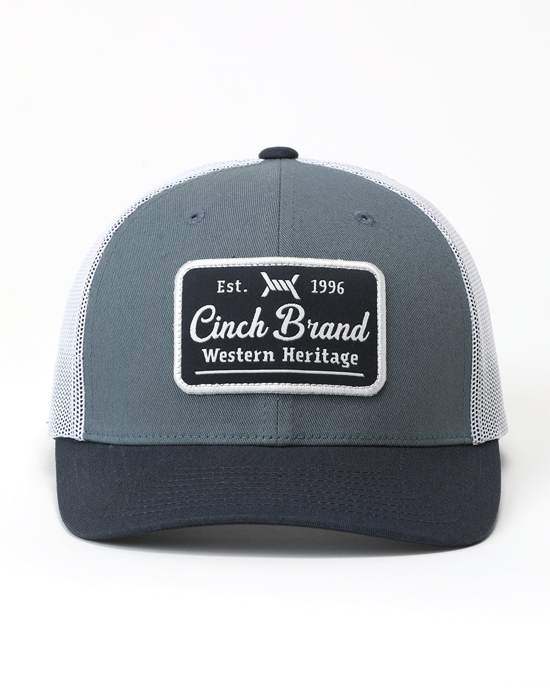 A gray and navy blue trucker hat with white mesh back panels and a black rectangular patch on the front that reads 'Cinch Brand Western Heritage'.