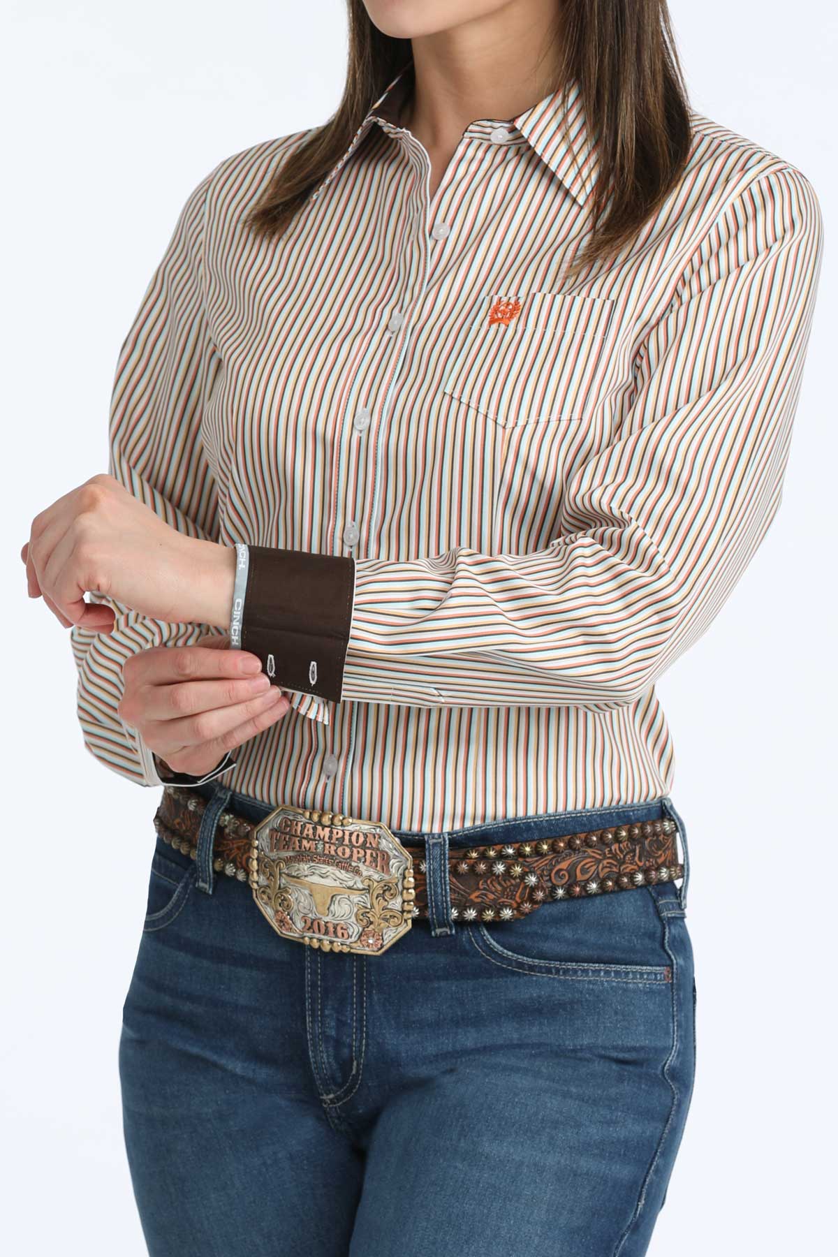 Woman wearing a striped 'Cinch' shirt and jeans with a belt, on a white background