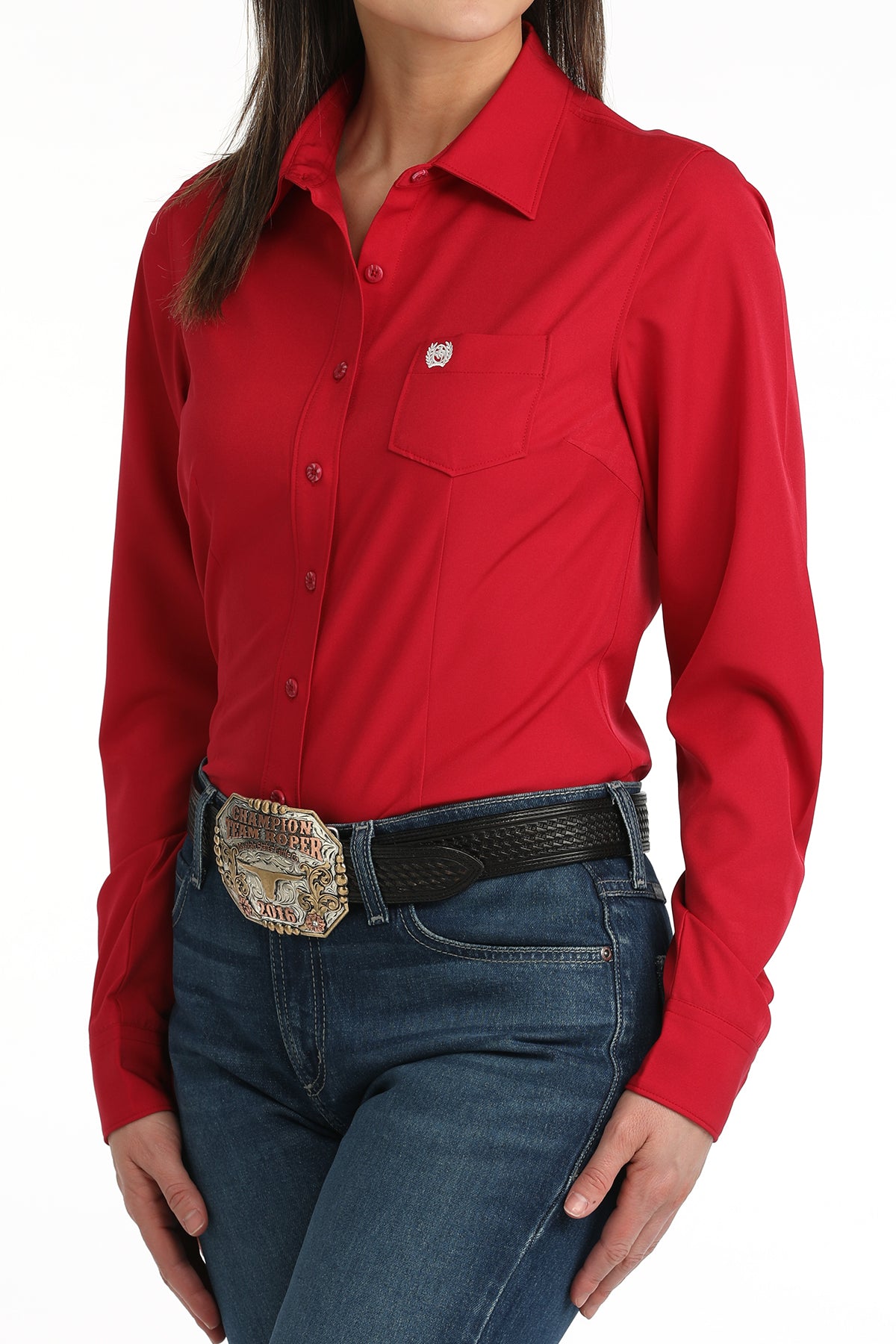 Woman wearing a pink cinch shirt and blue jeans with a belt buckle.