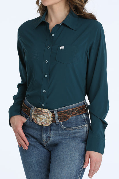 Person wearing a teal Cinch button-up shirt and jeans with a decorative belt on a white background