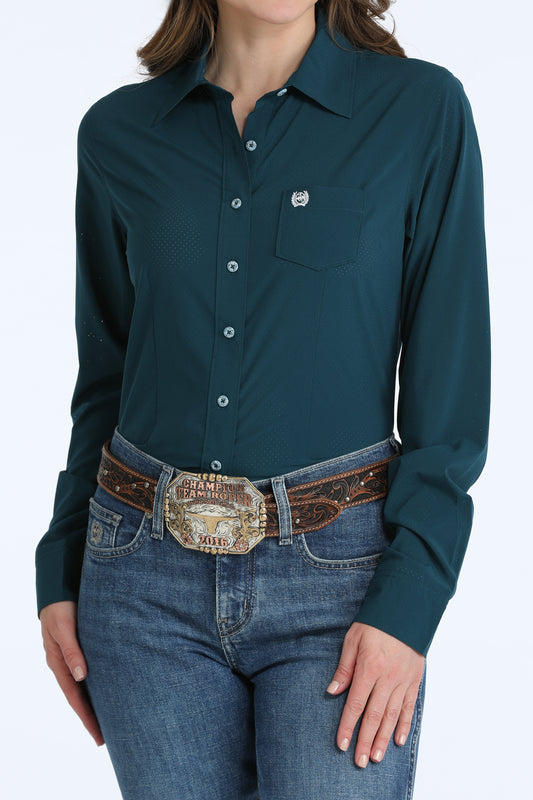 Person wearing a teal Cinch button-up shirt and jeans with a decorative belt on a white background