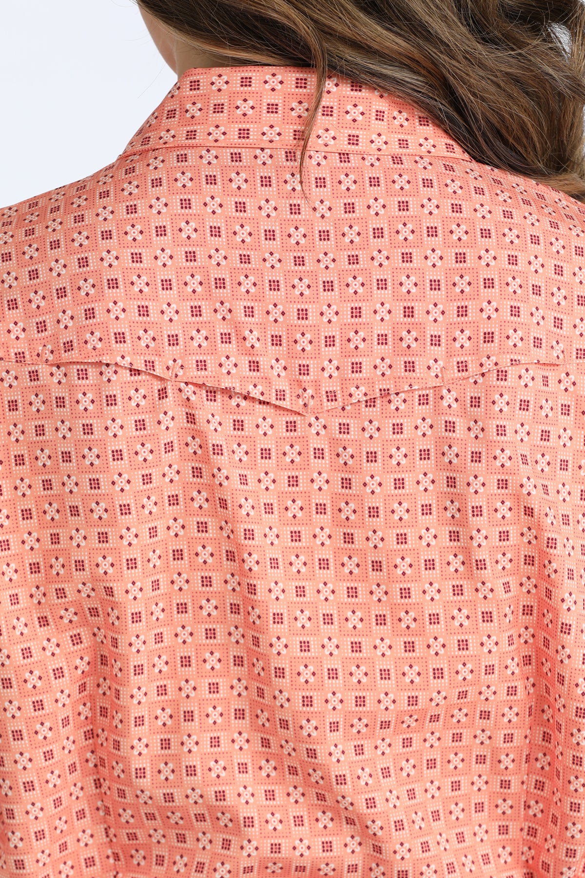 Close-up of a pink patterned Cinch shirt with a blurred background