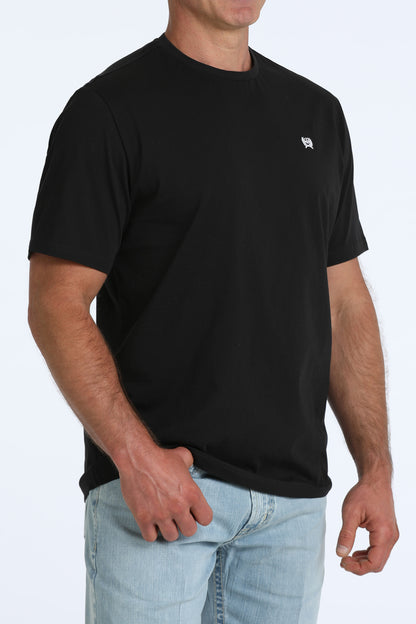 man wearing a black Cinch t shirt and blue jeans on a white background