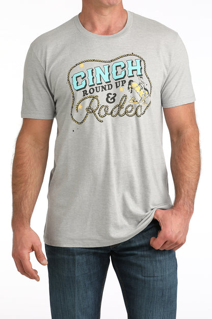 Man wearing a gray Cinch t-shirt with 'Cinch Round Up & Rodeo' graphic design.