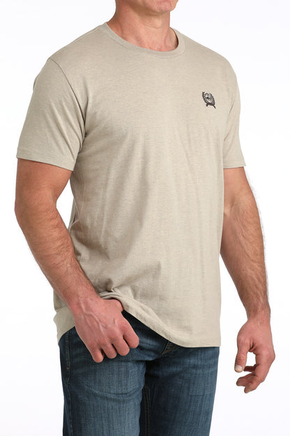 Man wearing a beige Cinch t-shirt with a small logo on a white background