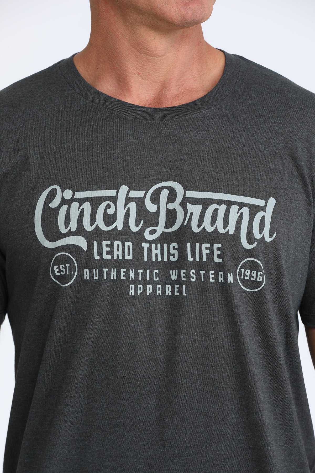 Person wearing a dark gray t-shirt with 'Cinch Brand' logo and text.