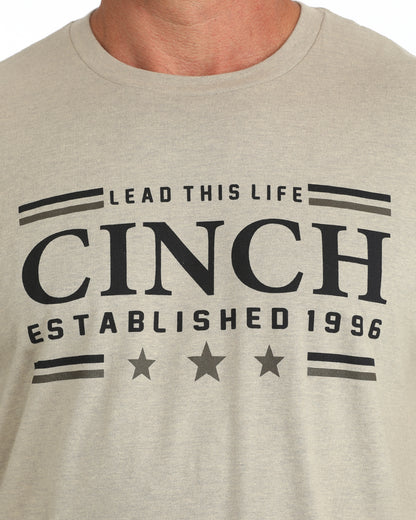 Man wearing a kahki Cinch tshirt on a white background
