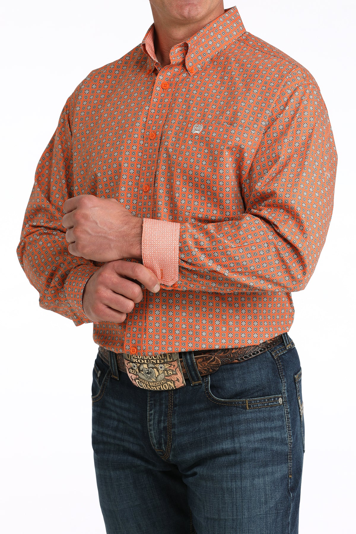 Man wearing an orange patterned 'Cinch' shirt and jeans on a white background