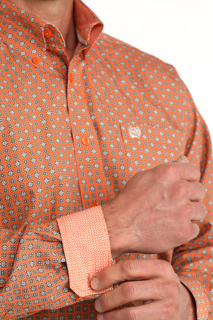 Close-up of an orange patterned 'Cinch' shirt with a person adjusting the sleeve.
