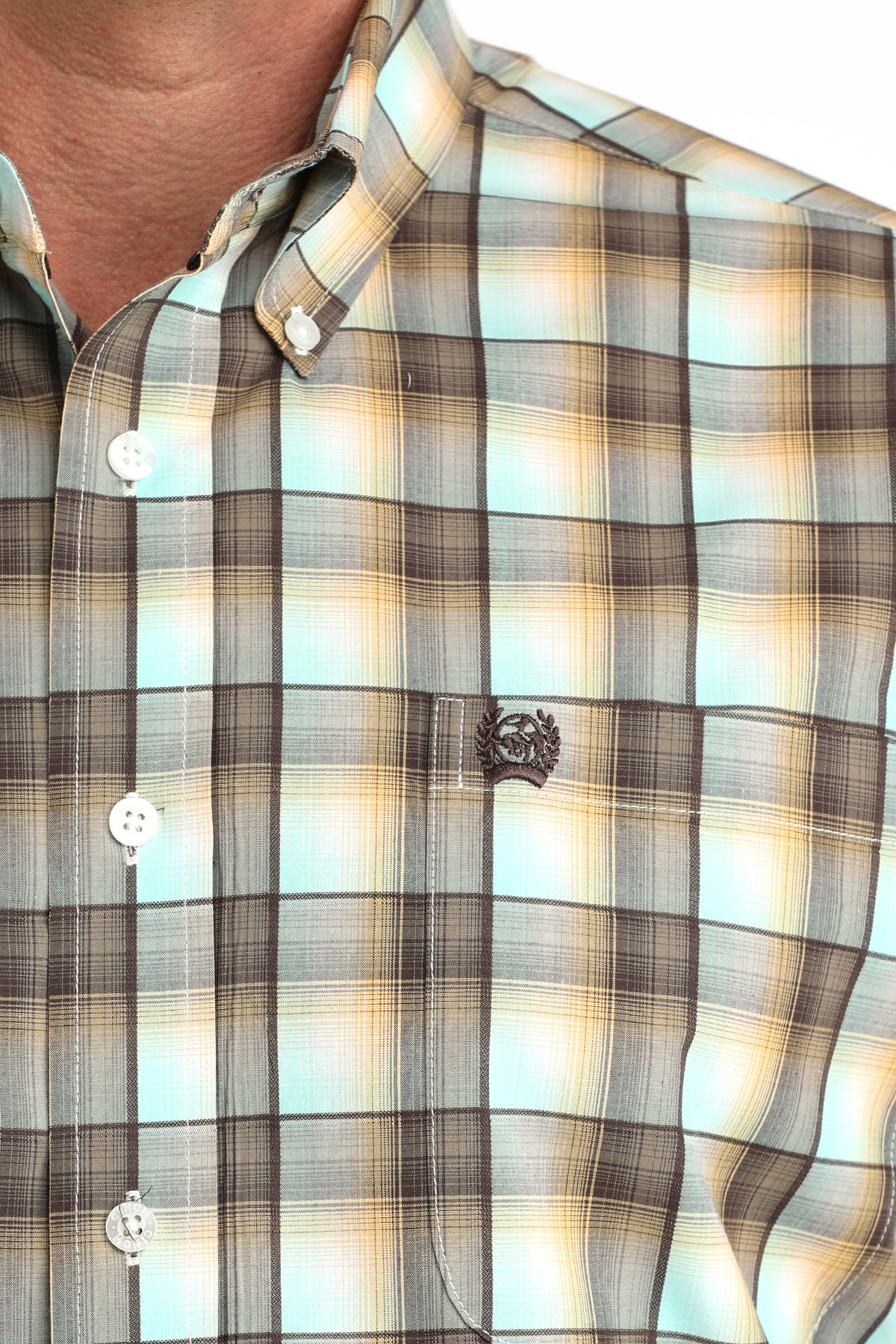 Close-up of a plaid 'Cinch' shirt with a brand logo on a blurred background