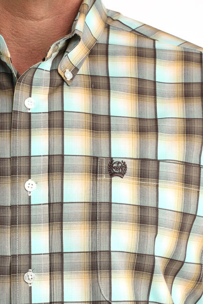 Close-up of a plaid 'Cinch' shirt with a brand logo on a blurred background