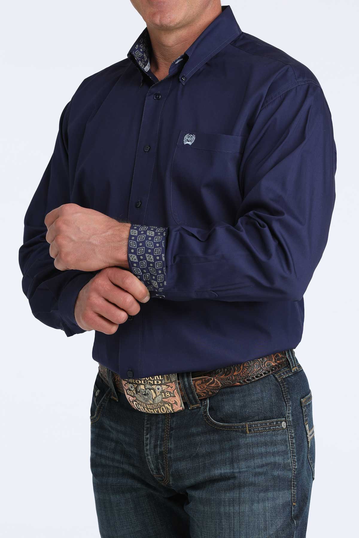 Person wearing a navy blue cinch shirt with a patterned cuff and jeans on a white background