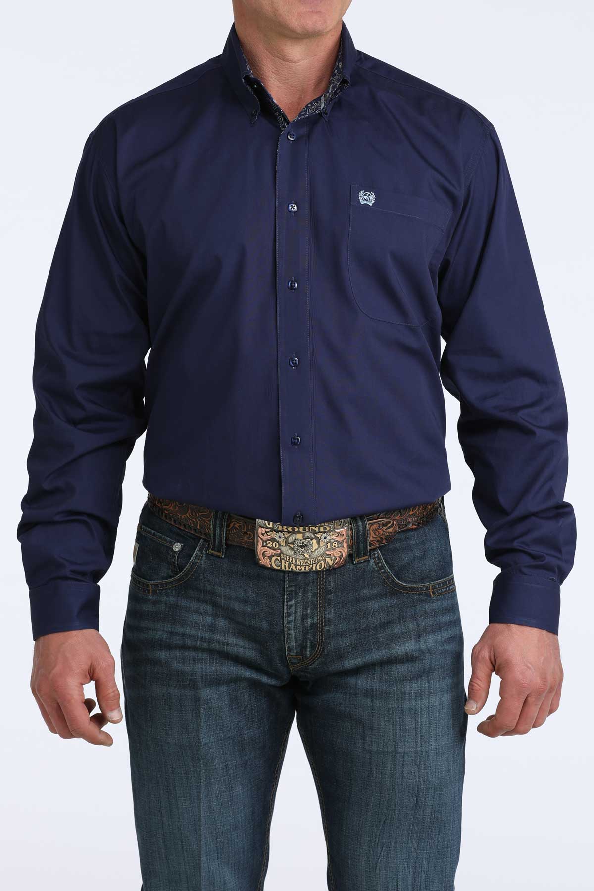 Man wearing a navy blue cinch button-up shirt and jeans on a white background