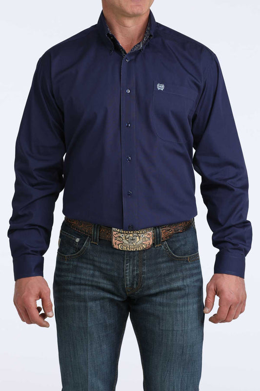 Man wearing a navy blue cinch button-up shirt and jeans on a white background