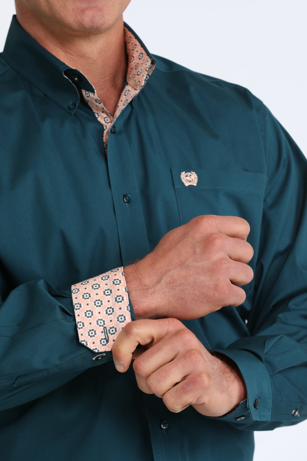 Man wearing a teal Cinch shirt with rolled-up sleeves on a white background