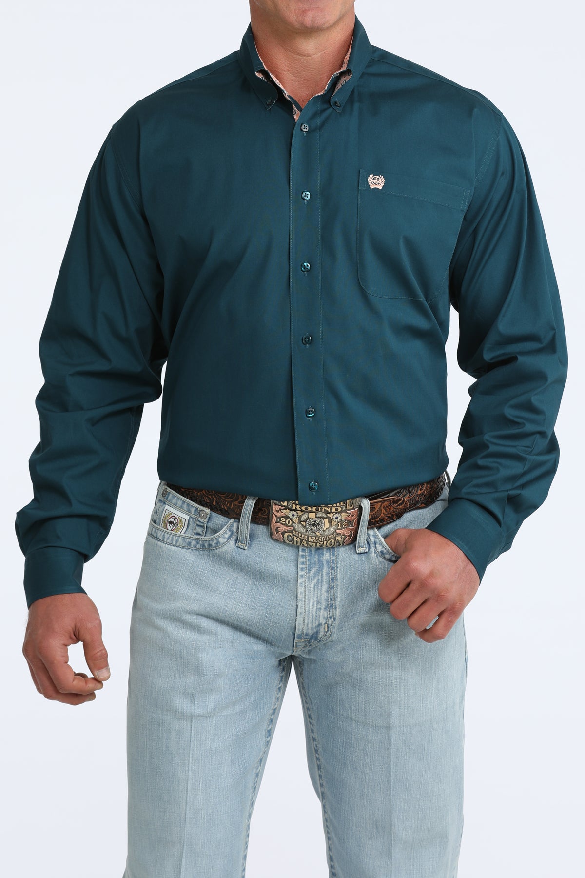 Man wearing a teal Cinch shirt  and light blue jeans on a white background