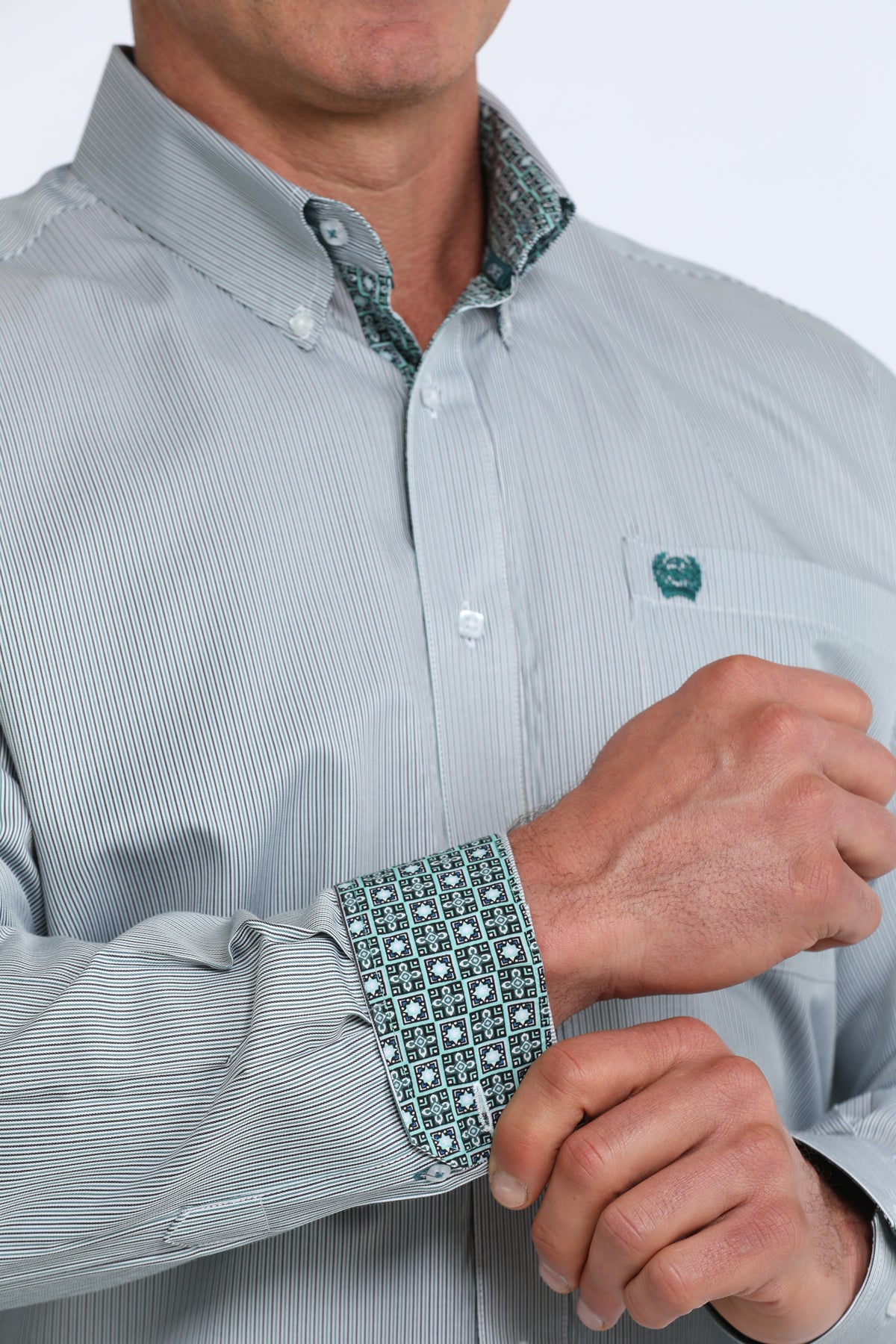 Close-up of a person wearing a light green Cinch dress shirt with patterned cuffs and collar.