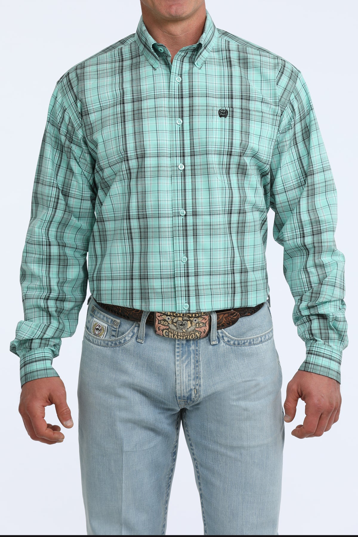 Man wearing a green plaid Cinch shirt and light blue jeans on a white background