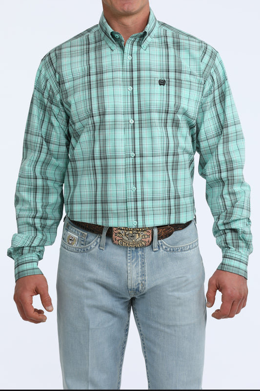 Man wearing a green plaid Cinch shirt and light blue jeans on a white background