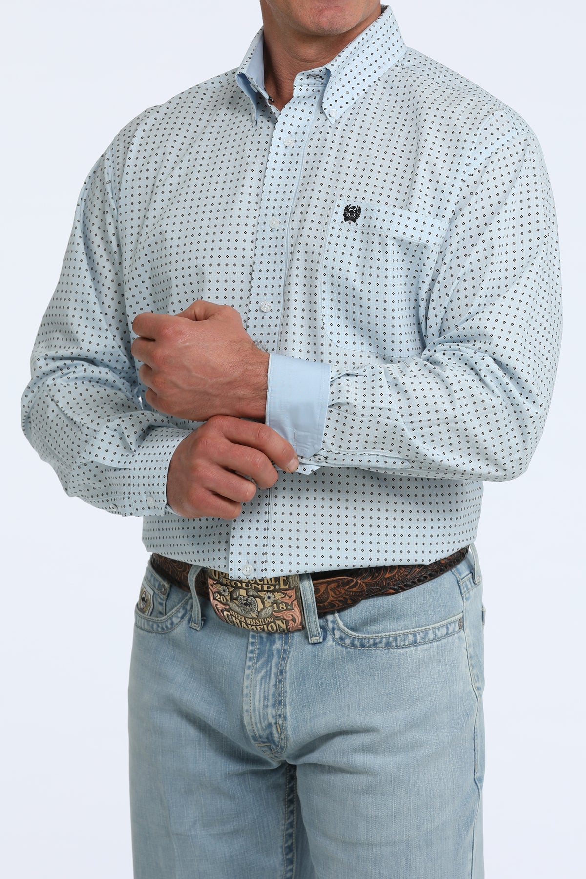 Man wearing a patterned Cinch shirt and jeans on a white background