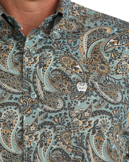 Close-up of a men's button-down Cinch shirt featuring an intricate paisley pattern in muted teal, brown, beige, and white. The fabric is worn by a model, with the collar and lower chest visible.