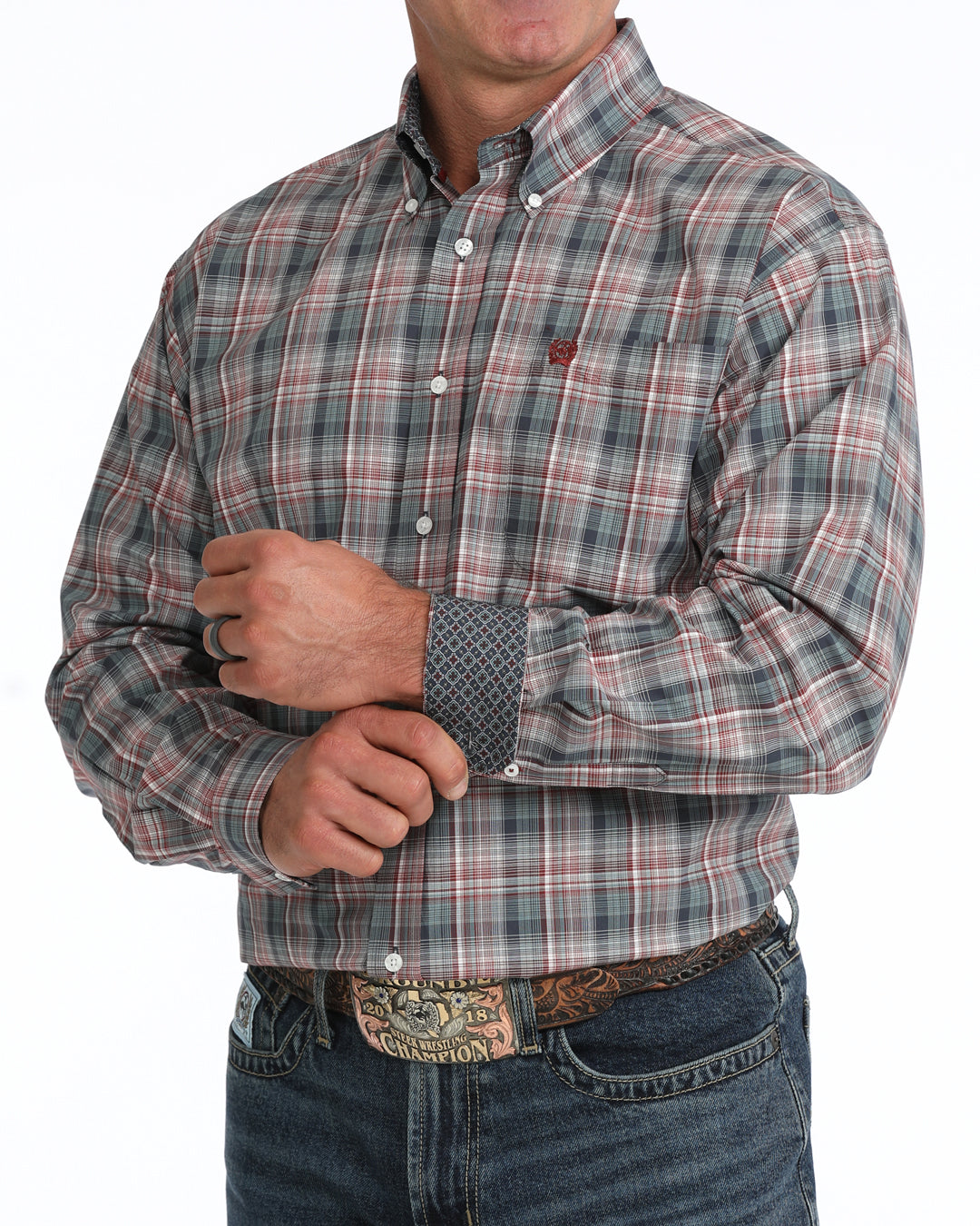A man wearing a long-sleeve button-down plaid Cinch shirt in muted gray, red, and green tones, paired with dark blue jeans and a western belt buckle, shown against a plain white background.