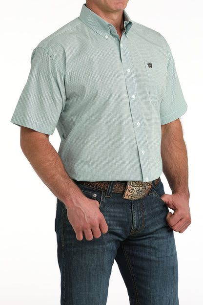 Man wearing a light blue short-sleeve  'Cinch' shirt and blue jeans on a white background