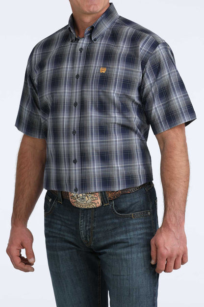 Man wearing a plaid cinch short sleeve shirt and jeans on a white background