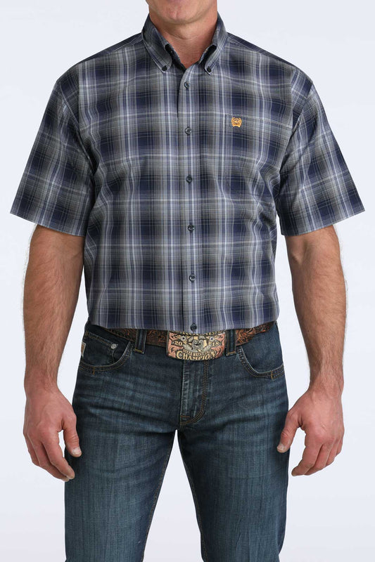 Man wearing a plaid cinch short sleeve shirt and jeans on a white background