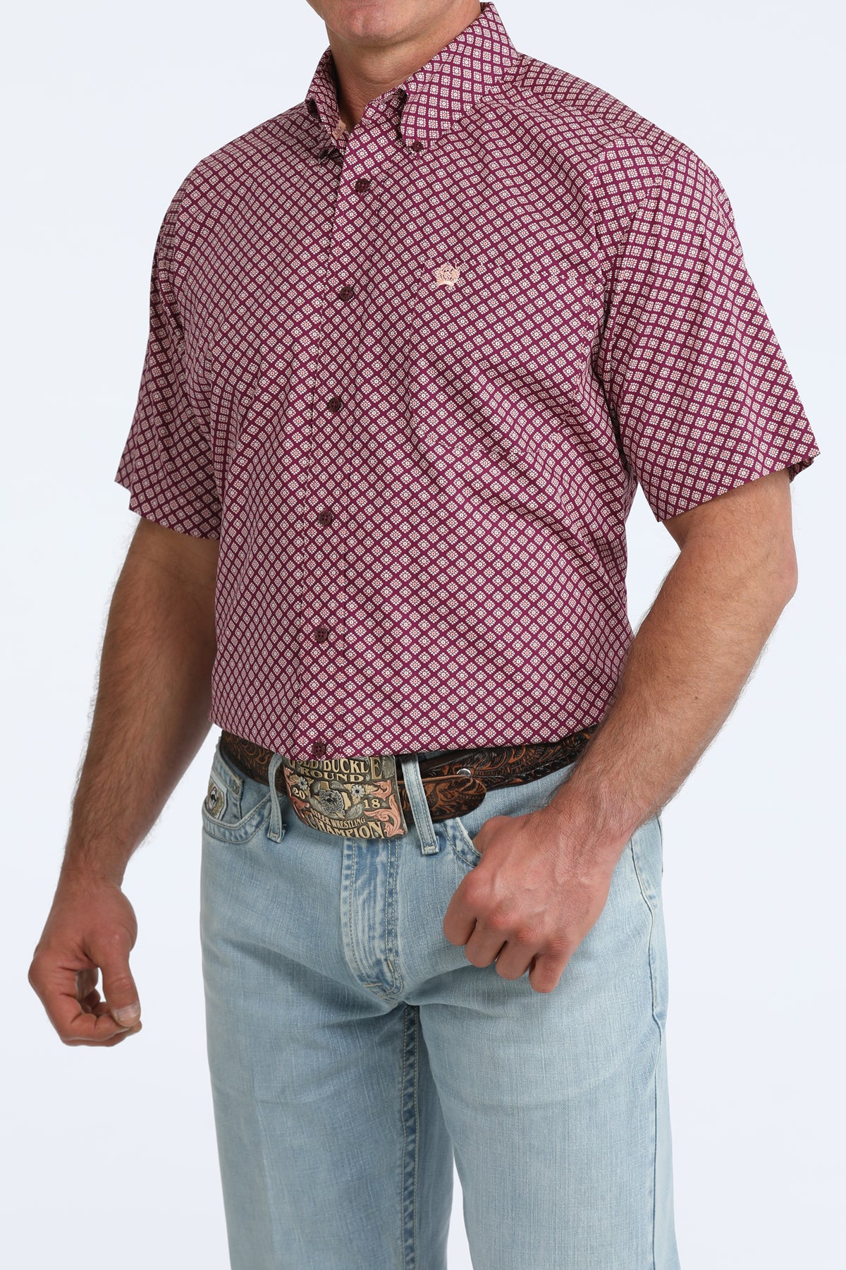 Man wearing a purple patterned Cinch shirt and light blue jeans on a white background