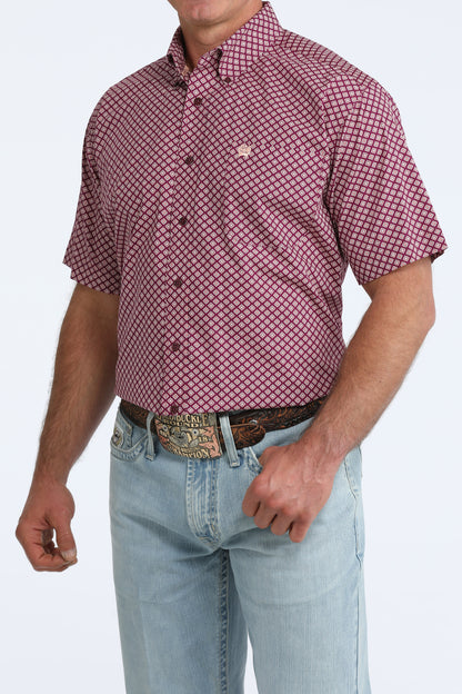 Man wearing a purple patterned Cinch shirt and light blue jeans on a white background