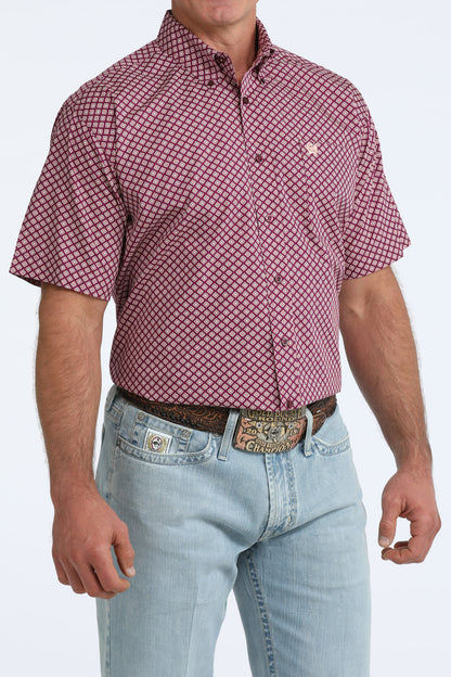 Man wearing a purple patterned Cinch shirt and light blue jeans on a white background