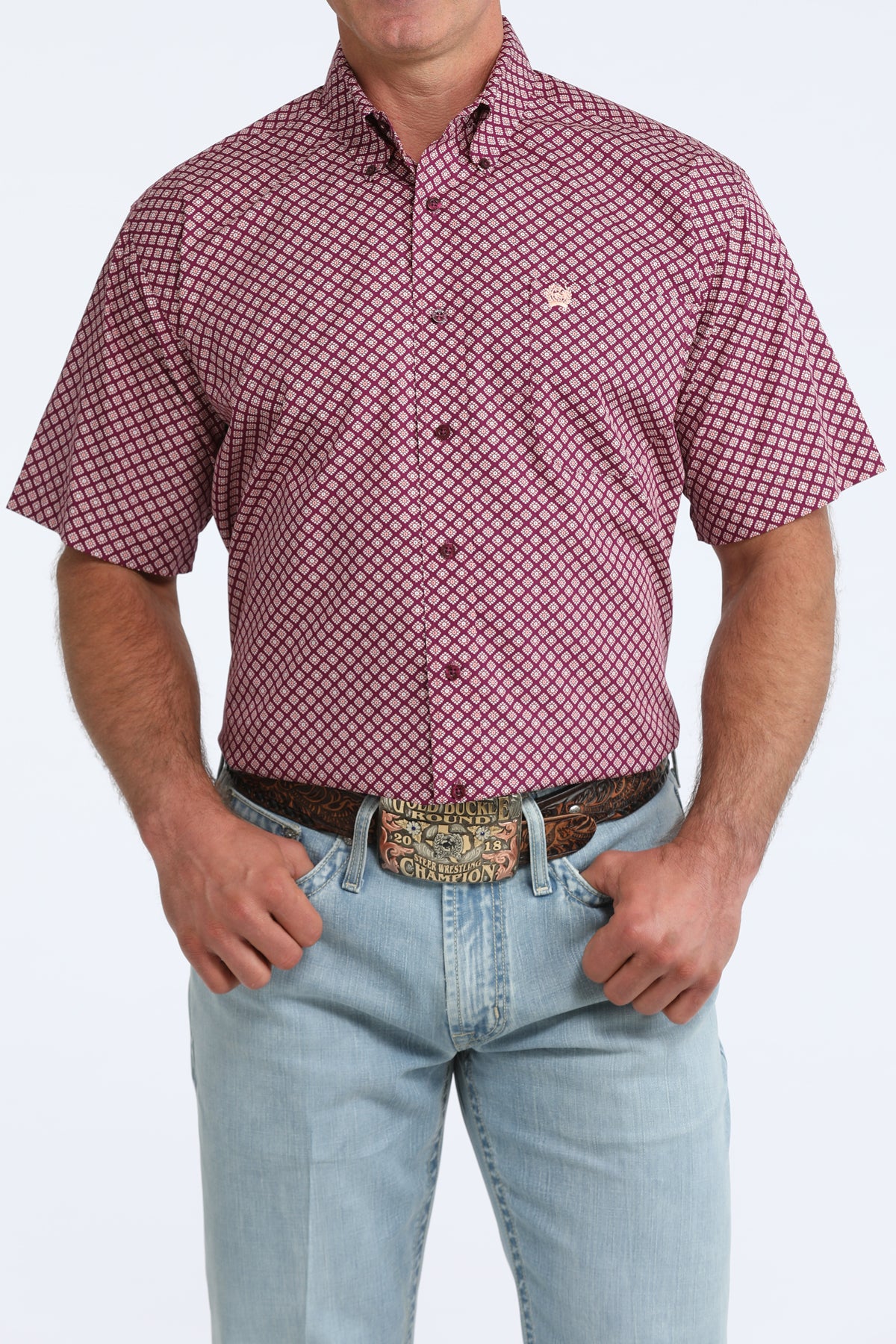 Man wearing a purple patterned Cinch shirt and light blue jeans on a white background