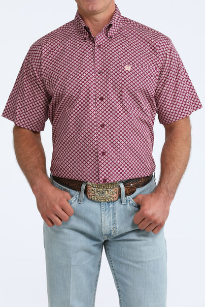 Man wearing a purple patterned Cinch shirt and light blue jeans on a white background