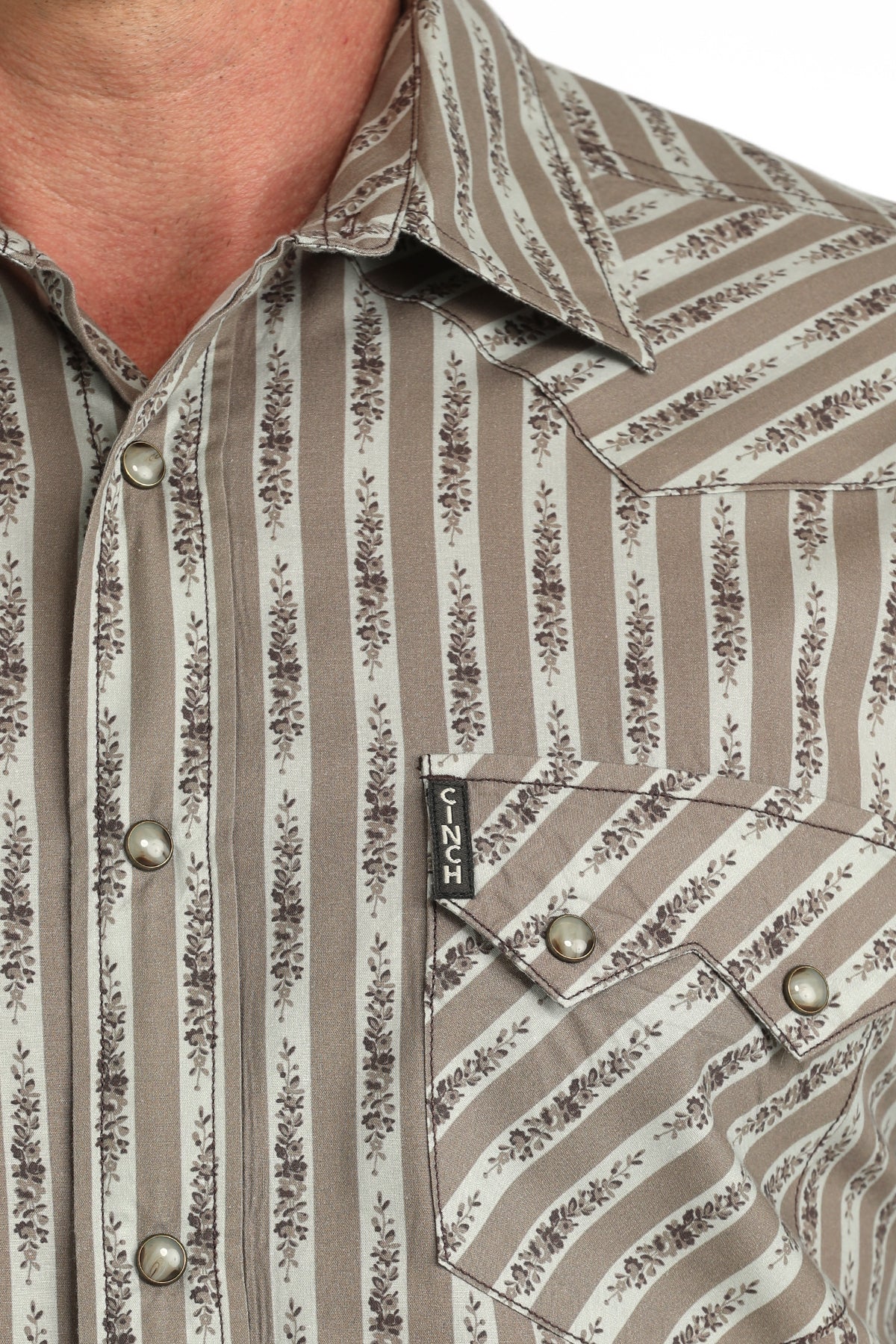 Close-up of a patterned 'Cinch' shirt with a brand logo on a pocket.