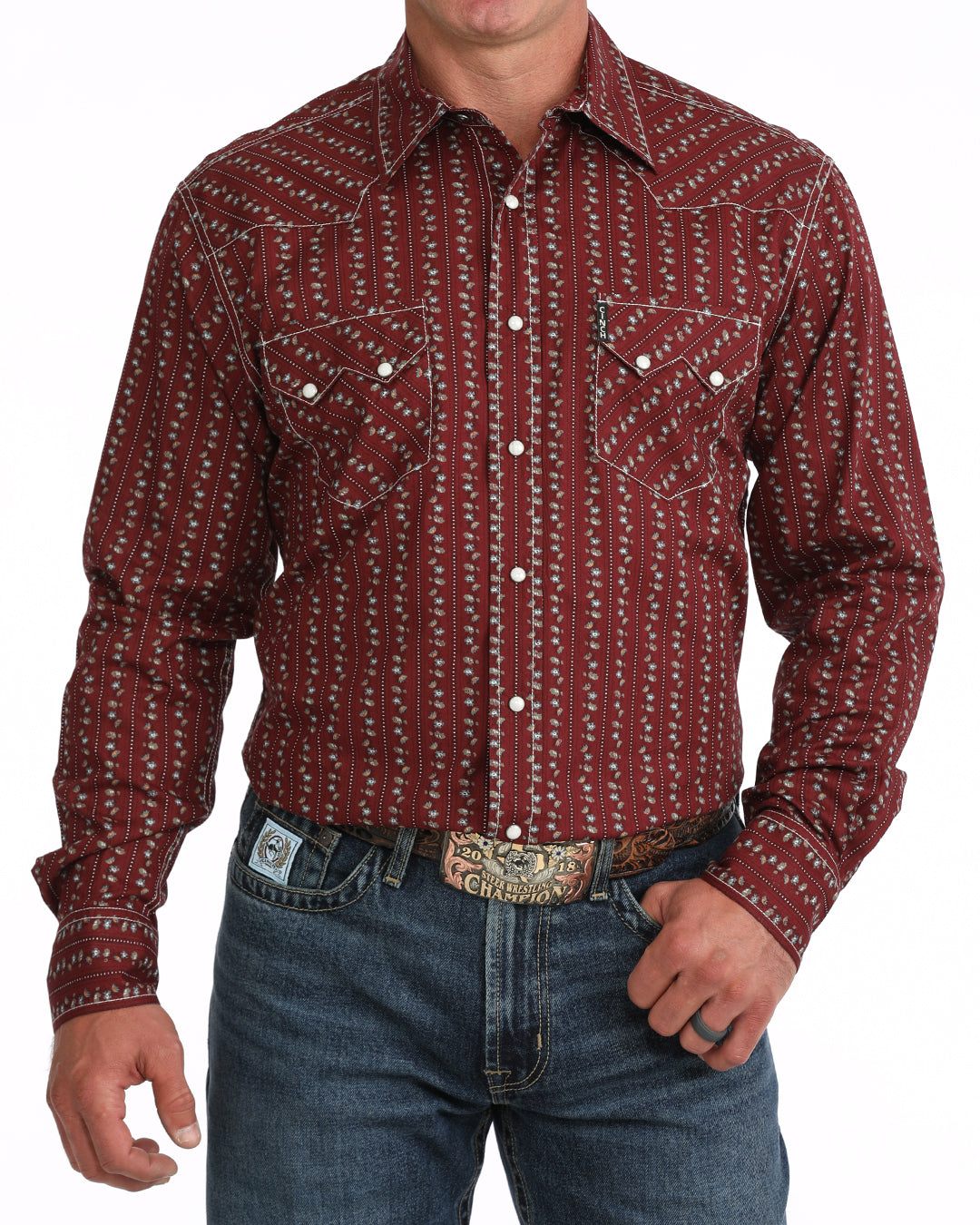 Man wearing a patterned red Cinch shirt and blue jeans on a white background