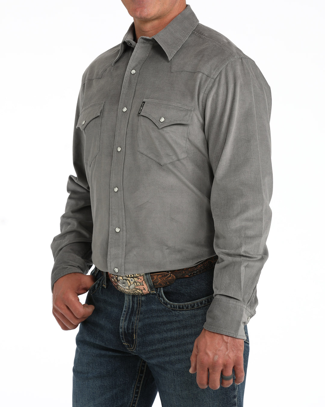 man wearing a grey corduroy Cinch shirt and blue jeans on a white background