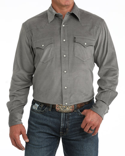man wearing a grey corduroy Cinch shirt and blue jeans on a white background