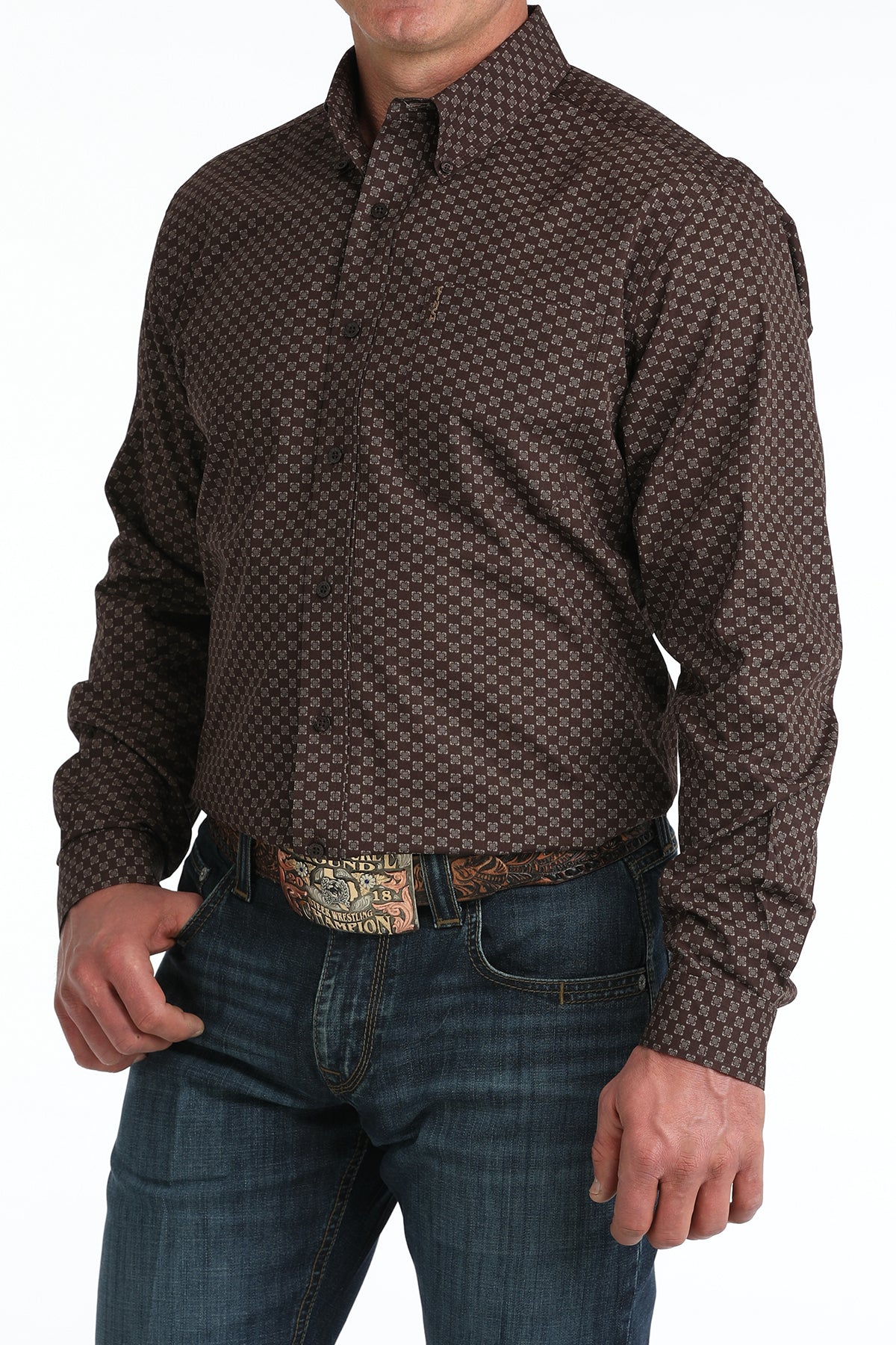 Man wearing a patterned brown 'Cinch' shirt and jeans with a belt.