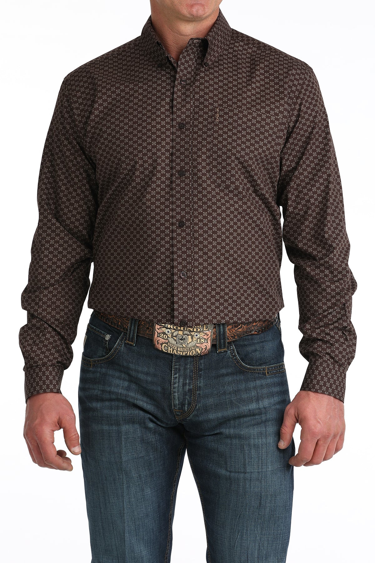 Man wearing a brown patterned 'Cinch' shirt and blue jeans with a belt on a white background